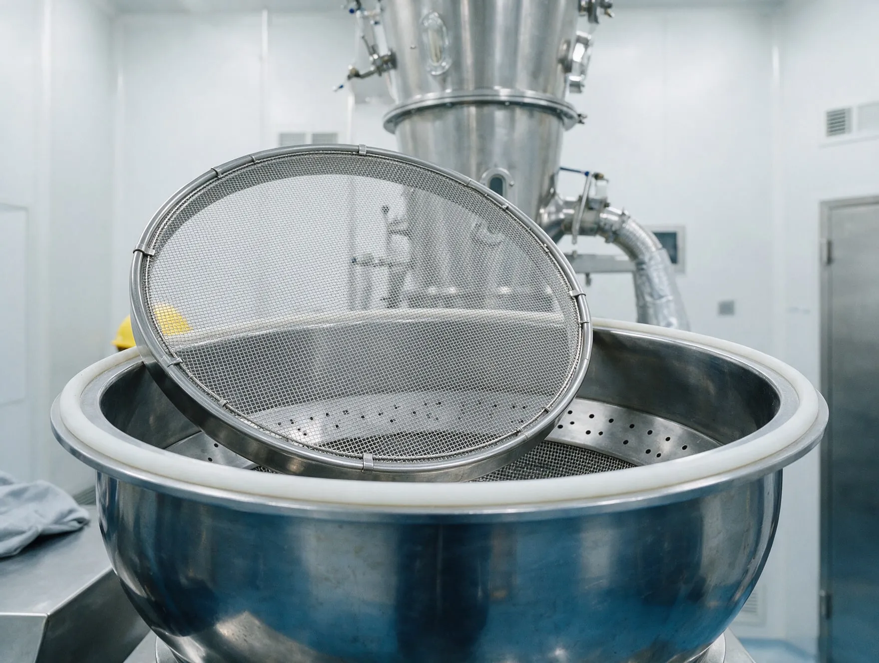 A fluid bed dryer sieve resting on the product bowl of a dryer in a clean room