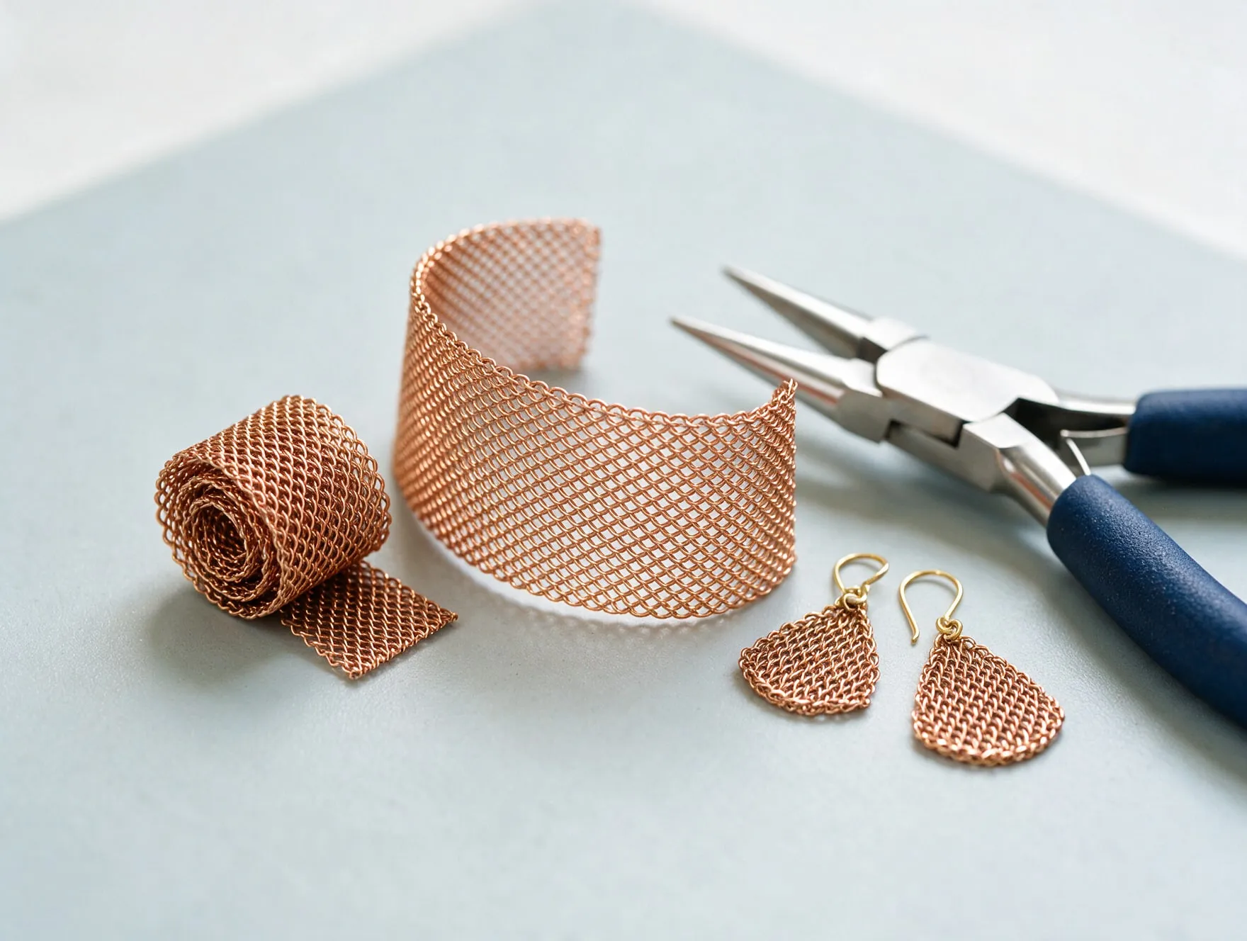 Fine phosphor bronze wire mesh shaped into a bracelet and earrings on a jeweller's bench