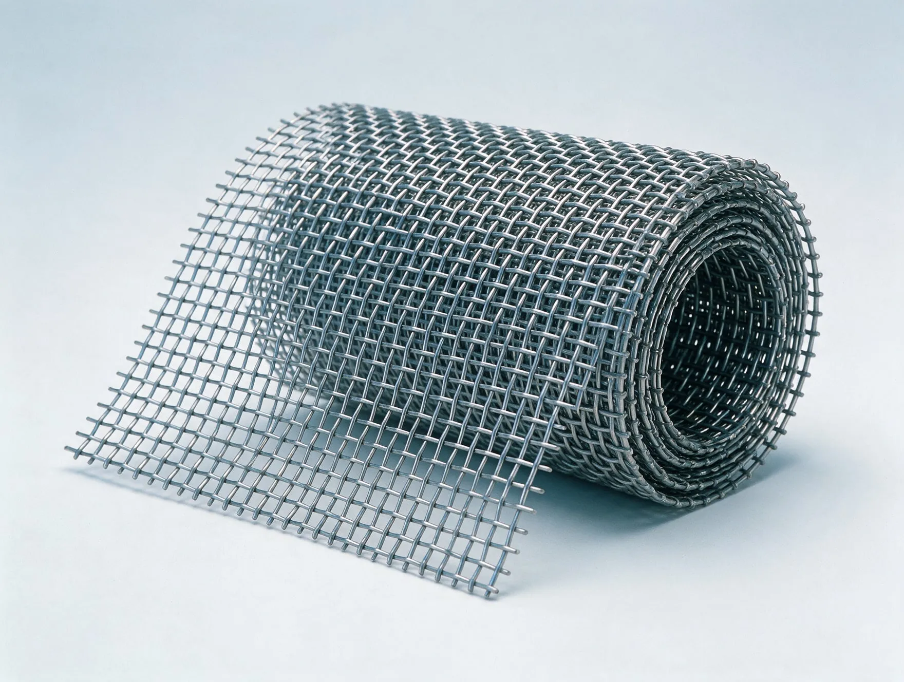 A roll of crimped woven wire mesh in stainless steel, partly unrolled