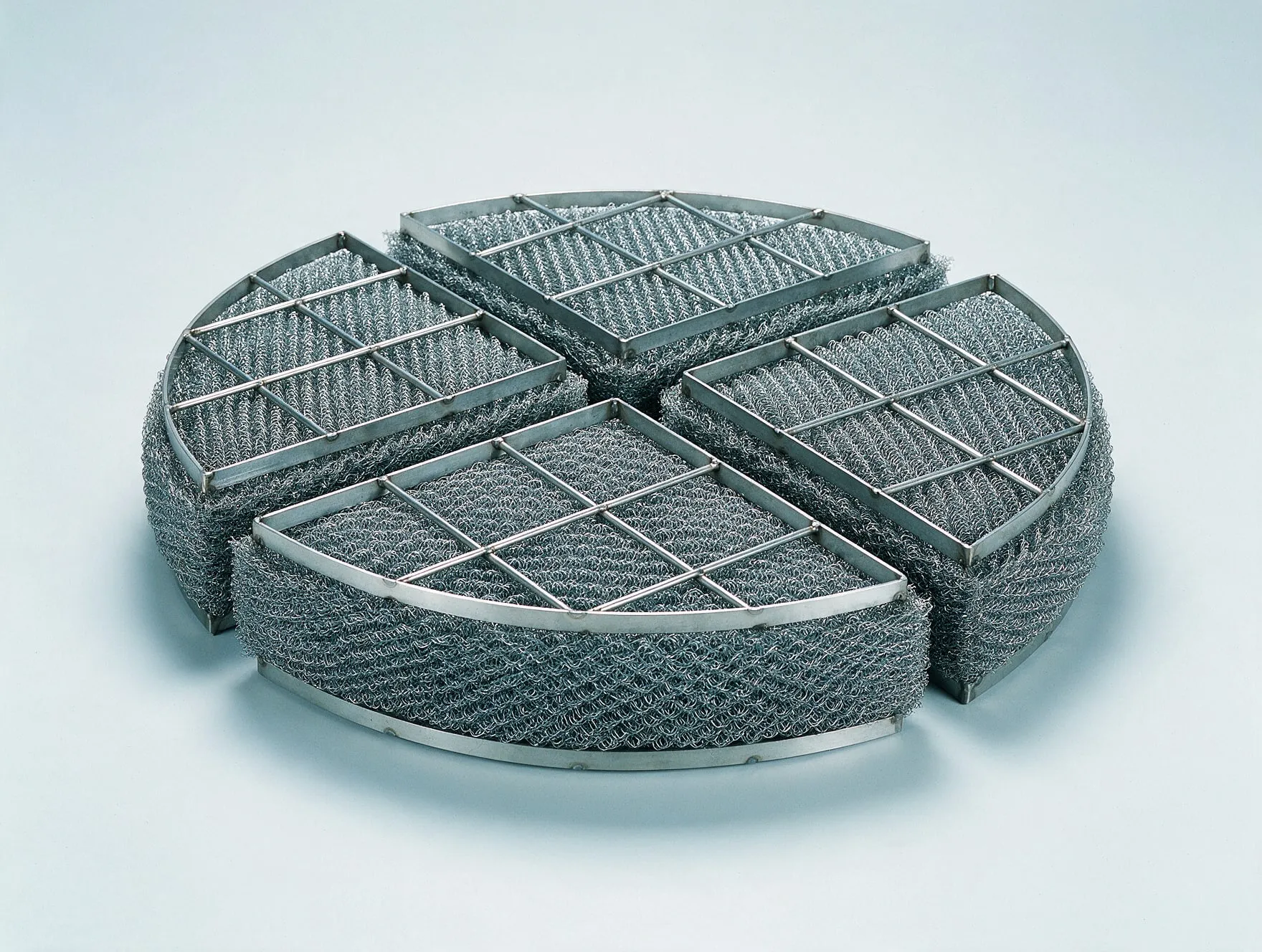 A round demister pad in sections, knitted mesh between support grids