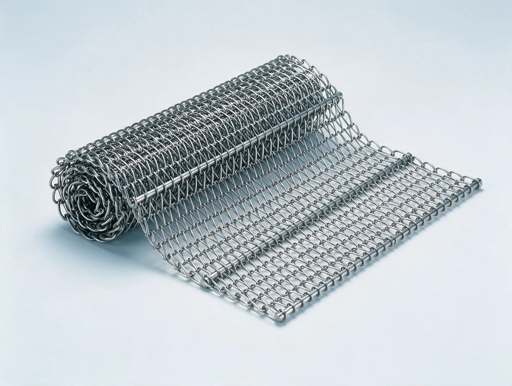 A length of stainless steel wire mesh conveyor belt, one end rolled