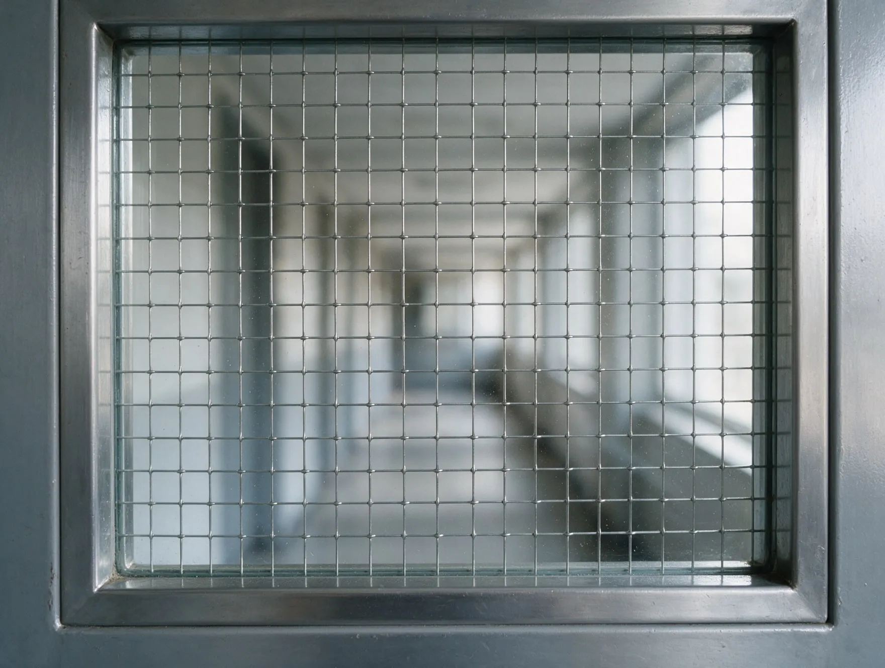 A pane of wired safety glass in a fire door, with a steel wire grid inside the glass